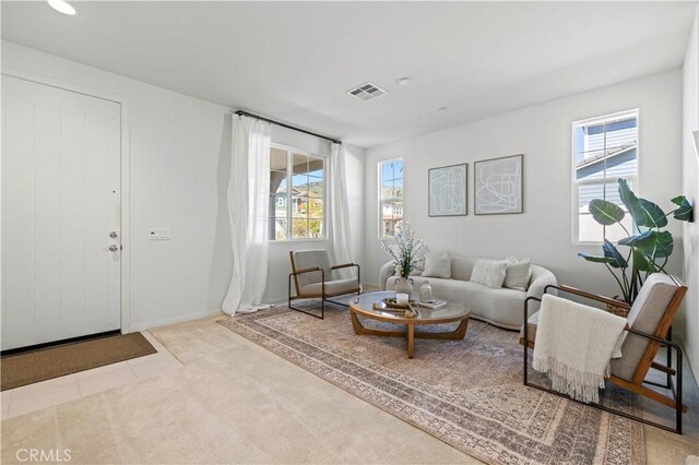 carpeted living area featuring visible vents and plenty of natural light