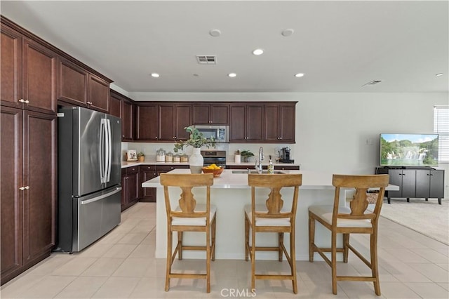 kitchen featuring visible vents, recessed lighting, appliances with stainless steel finishes, light countertops, and a center island with sink