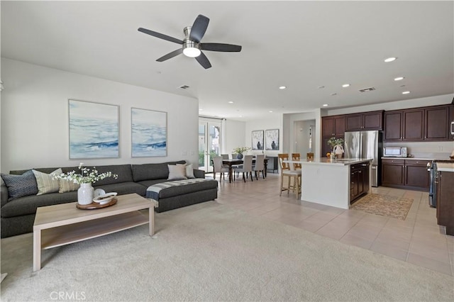 living area featuring light tile patterned floors, light colored carpet, a ceiling fan, visible vents, and recessed lighting