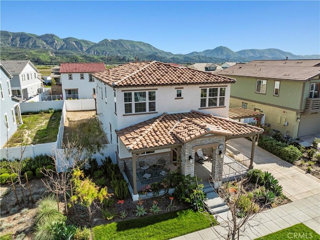 exterior space featuring a mountain view, a fenced backyard, a tile roof, and a residential view