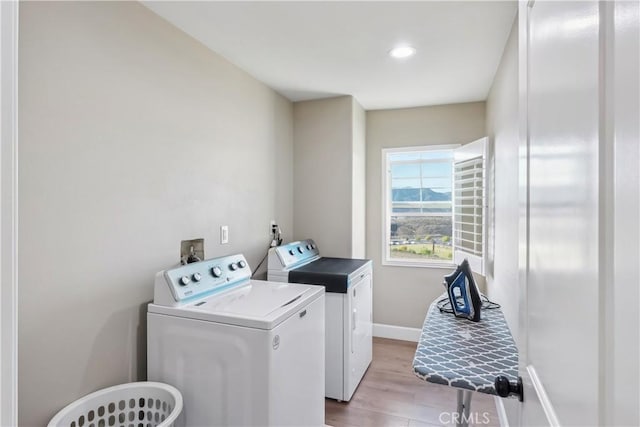 laundry area with light wood-style floors, washing machine and dryer, laundry area, and baseboards