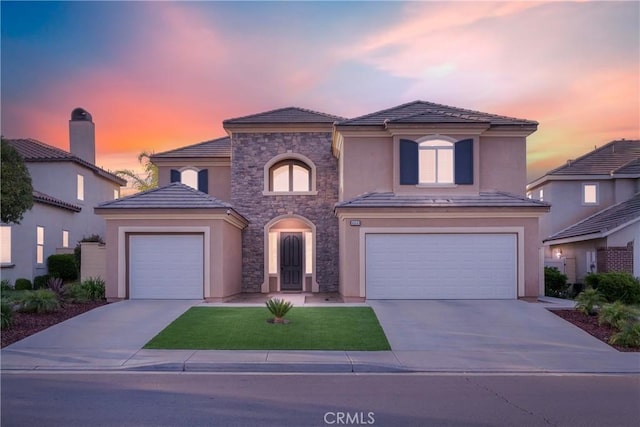 mediterranean / spanish house with concrete driveway, stucco siding, stone siding, and a tile roof