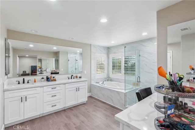 full bathroom with a sink, a bath, a shower stall, and wood finished floors