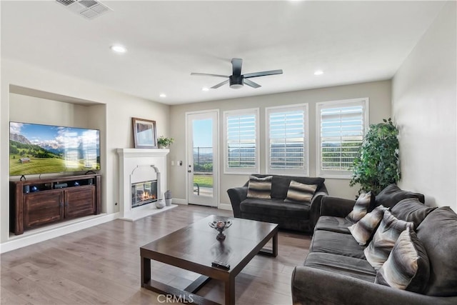 living room featuring visible vents, a ceiling fan, light wood-style flooring, and a healthy amount of sunlight