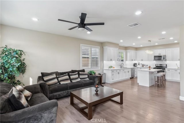 living area featuring recessed lighting, light wood finished floors, visible vents, and ceiling fan
