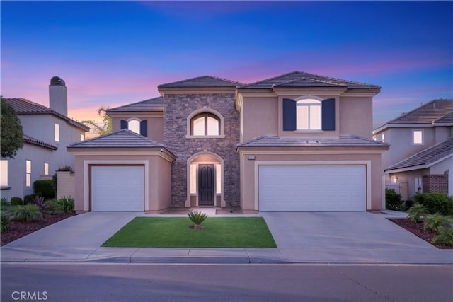 mediterranean / spanish home with concrete driveway, stucco siding, stone siding, and a tile roof