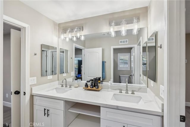 bathroom with double vanity, visible vents, a sink, and toilet