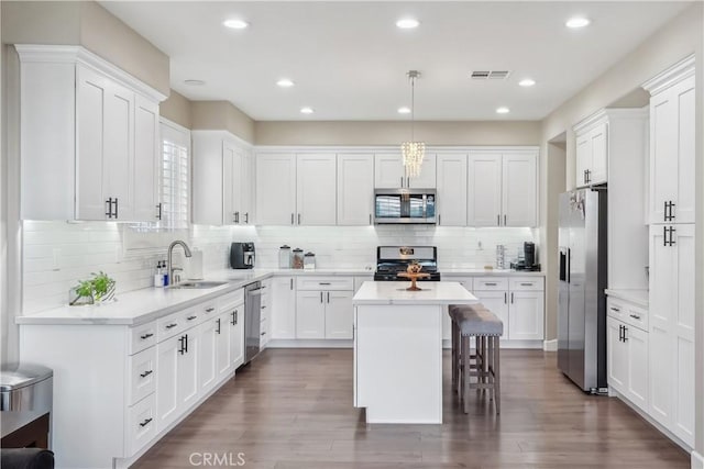 kitchen with stainless steel appliances, white cabinets, a sink, and a kitchen island