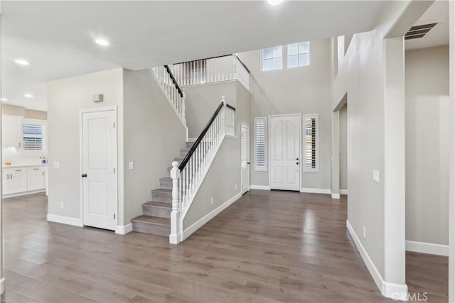foyer entrance featuring stairway, wood finished floors, visible vents, and a healthy amount of sunlight