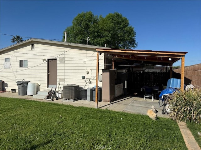 rear view of house with fence, a lawn, and central air condition unit