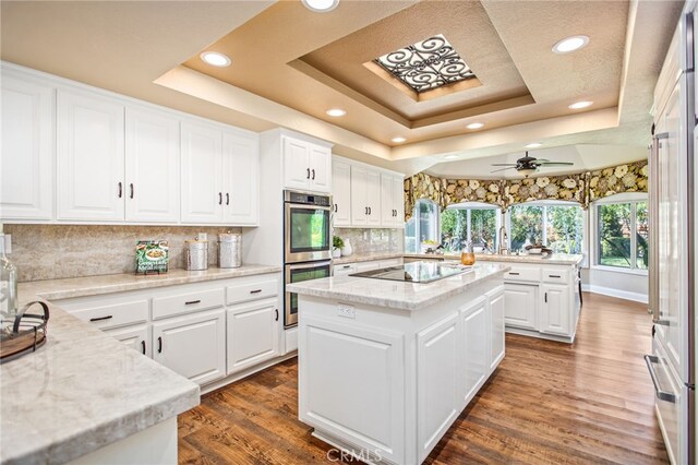 22316 Bear Creek Dr S, Murrieta, CA 92562 - kitchen featuring black electric cooktop, a tray ceiling, recessed lighting, stainless steel double oven, and a kitchen island