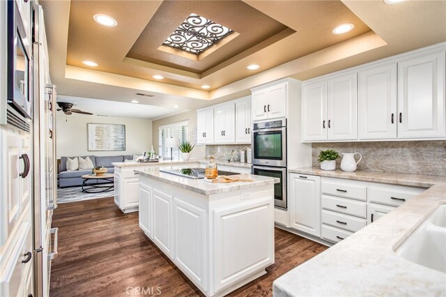 22316 Bear Creek Dr S, Murrieta, CA 92562 - kitchen with white cabinetry, stainless steel double oven, and a raised ceiling