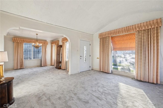 foyer entrance with a chandelier, carpet flooring, and a wealth of natural light