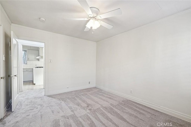 empty room featuring crown molding, ceiling fan, light carpet, and baseboards