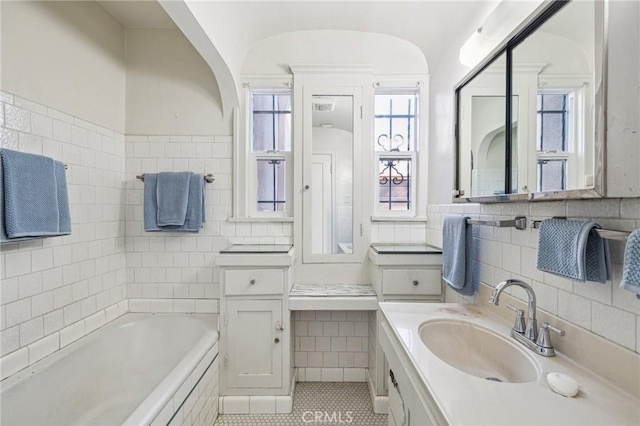 bathroom with tile walls, a garden tub, and a healthy amount of sunlight