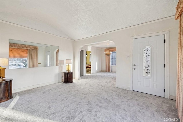 entryway featuring an inviting chandelier, carpet, a textured ceiling, arched walkways, and vaulted ceiling
