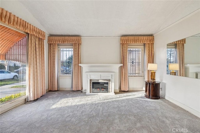 unfurnished living room with a glass covered fireplace, lofted ceiling, a textured ceiling, and carpet floors