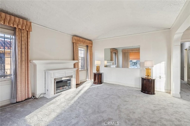 unfurnished living room featuring carpet, a glass covered fireplace, vaulted ceiling, and a textured ceiling