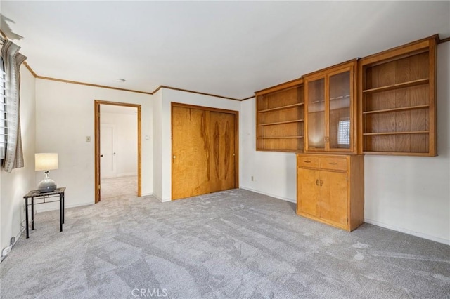 unfurnished bedroom featuring light carpet, baseboards, a closet, and crown molding