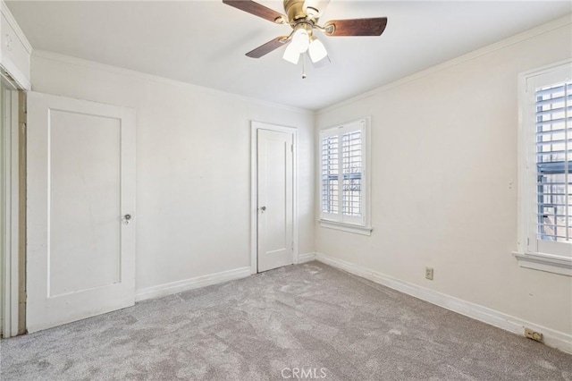 unfurnished bedroom with carpet flooring, baseboards, crown molding, and ceiling fan
