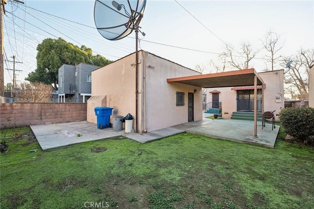 back of property with fence, a patio, a lawn, and stucco siding