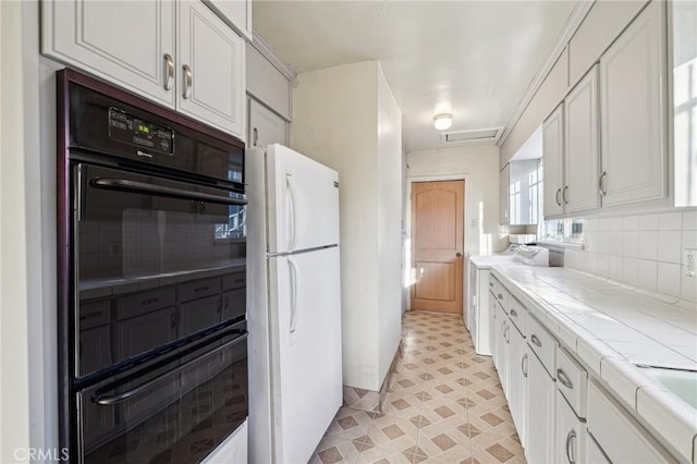 kitchen featuring white cabinetry, tile counters, backsplash, and freestanding refrigerator