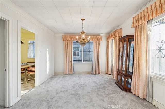 unfurnished dining area with crown molding, carpet floors, and an inviting chandelier