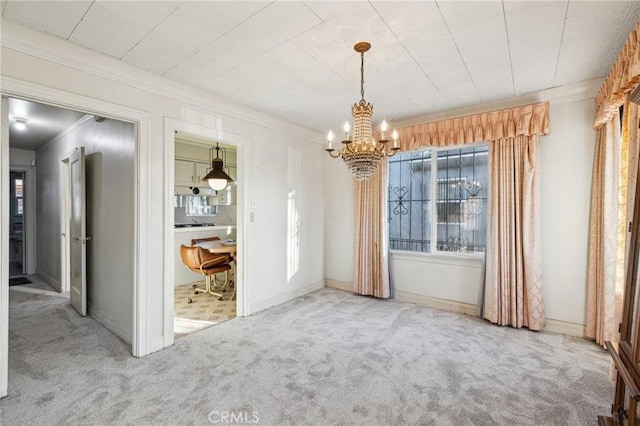 unfurnished dining area with a chandelier, crown molding, baseboards, and carpet