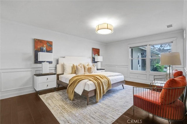 bedroom with visible vents, ornamental molding, dark wood-type flooring, and a decorative wall