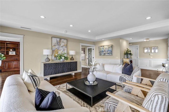living area with recessed lighting, wood finished floors, ornamental molding, visible vents, and a raised ceiling