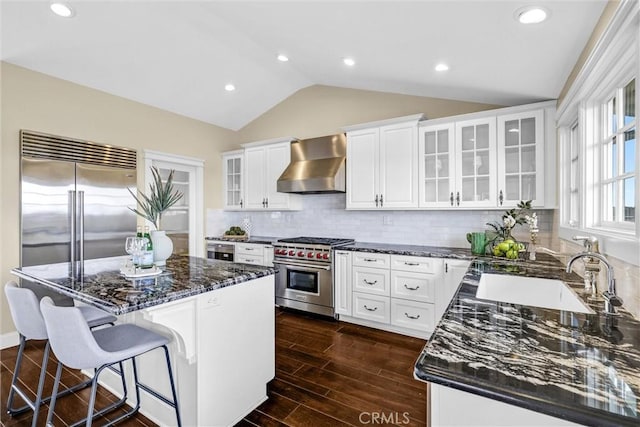 kitchen featuring lofted ceiling, a sink, a center island, wall chimney exhaust hood, and high end appliances