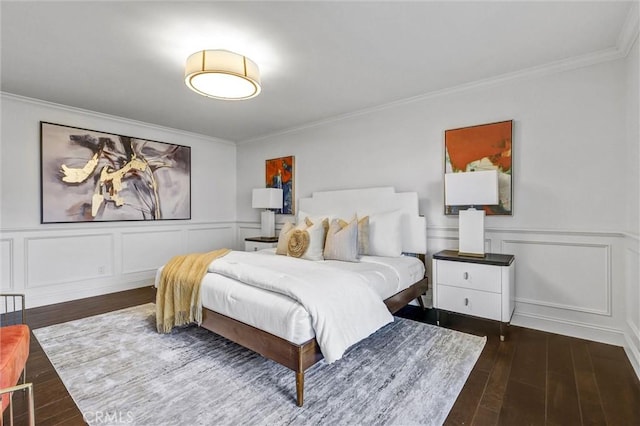 bedroom with crown molding, a wainscoted wall, a decorative wall, and wood finished floors