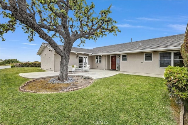 rear view of property with stucco siding, a patio area, a lawn, and french doors