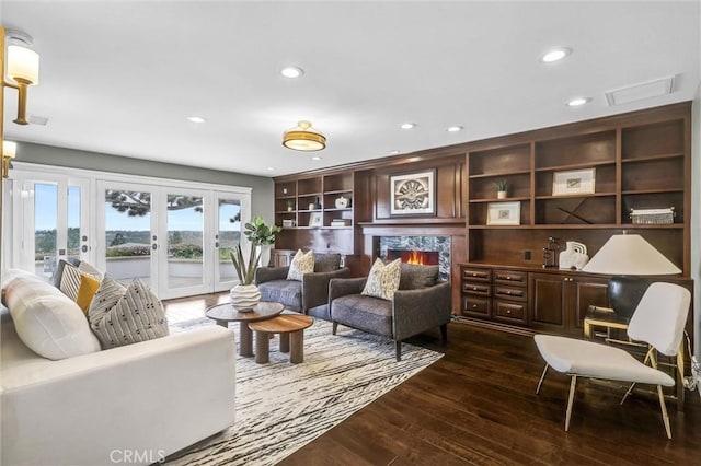 living area featuring visible vents, a lit fireplace, recessed lighting, dark wood finished floors, and french doors