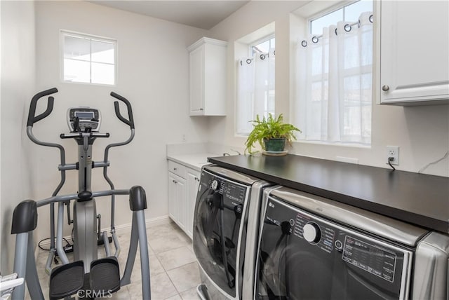 clothes washing area with baseboards, washer and clothes dryer, light tile patterned floors, and cabinet space