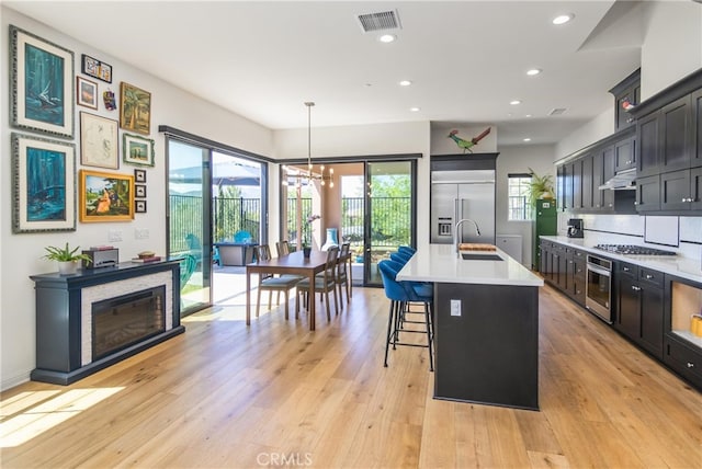 kitchen with under cabinet range hood, light countertops, visible vents, a sink, and appliances with stainless steel finishes