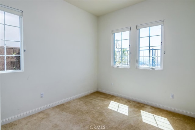 carpeted spare room featuring plenty of natural light and baseboards