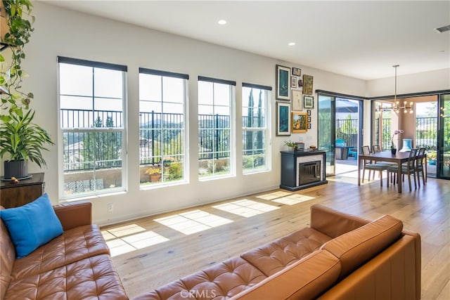 living area with recessed lighting, an inviting chandelier, visible vents, and light wood-type flooring