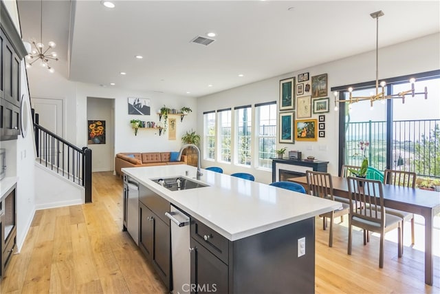 kitchen featuring light wood finished floors, visible vents, a sink, and a notable chandelier