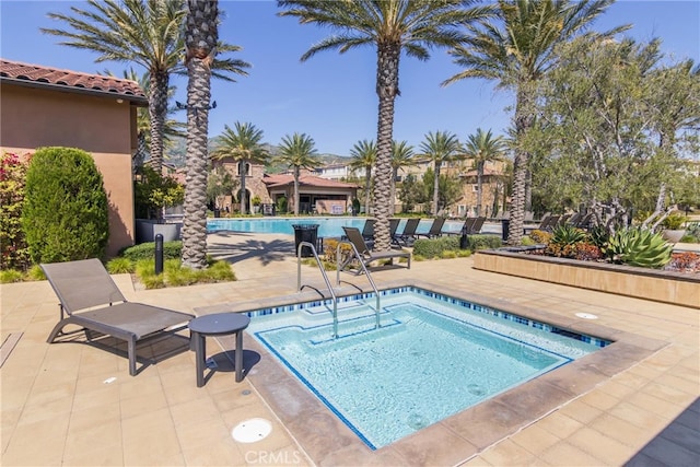 community pool with a patio area and a community hot tub