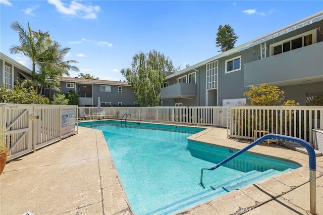 community pool with a patio and fence