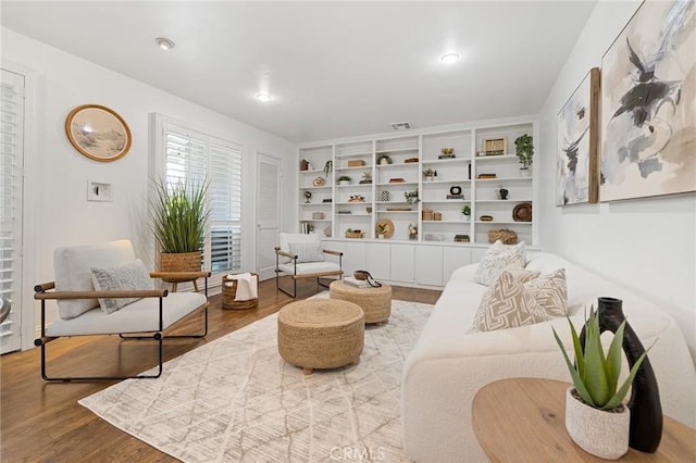 living area featuring visible vents, built in features, and wood finished floors