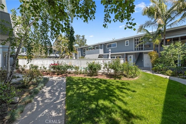 view of community featuring a yard, fence, and stairway
