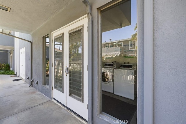entrance to property with visible vents, independent washer and dryer, and stucco siding