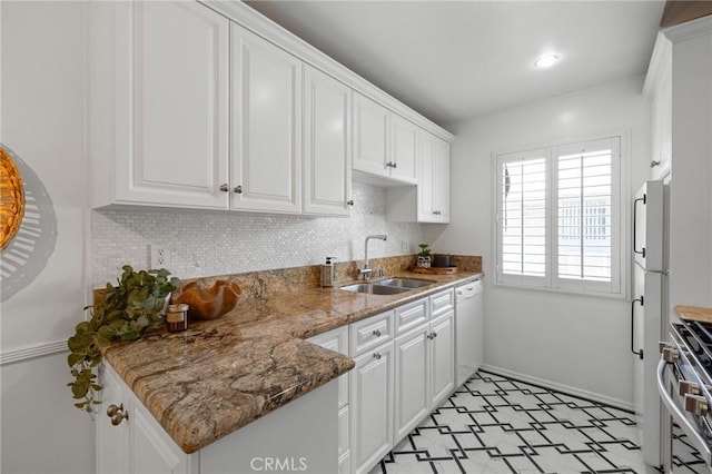 kitchen with stone countertops, white appliances, white cabinetry, decorative backsplash, and a sink