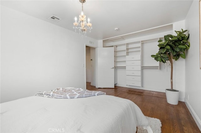 bedroom with visible vents, baseboards, a notable chandelier, and wood finished floors