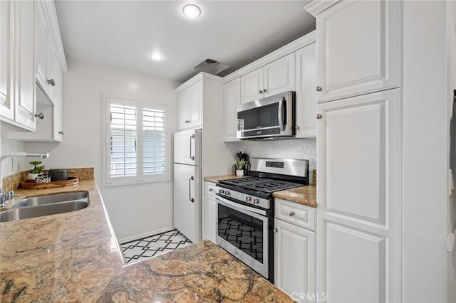 kitchen with baseboards, light countertops, white cabinets, decorative backsplash, and stainless steel appliances