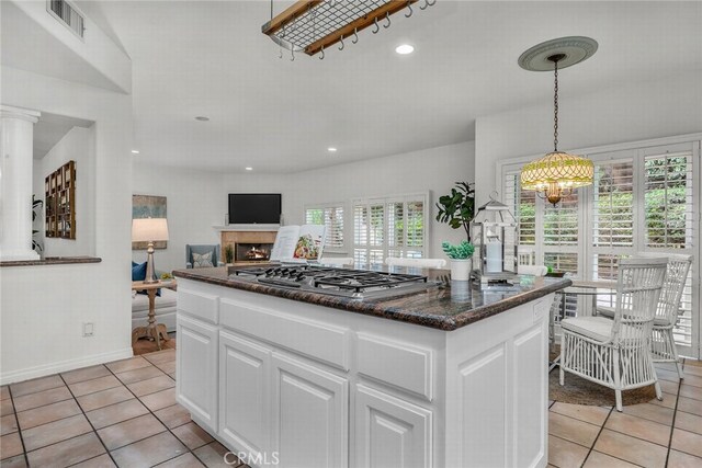 kitchen with pendant lighting, light tile patterned floors, stainless steel gas stovetop, white cabinetry, and visible vents