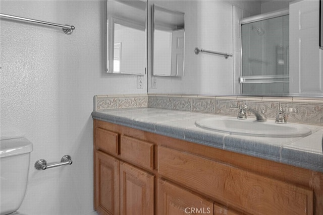 bathroom with toilet, a shower stall, and vanity
