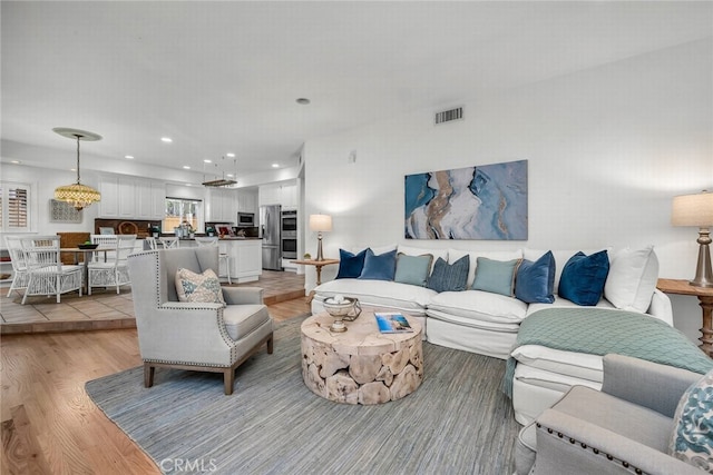 living area with light wood-type flooring, visible vents, and recessed lighting